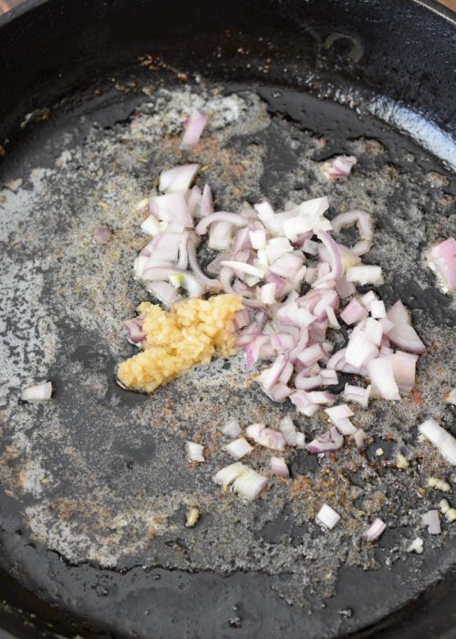 chopped shallots and garlic sauteeing in butter in a cast iron pan