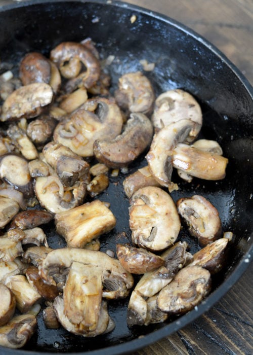 cremini mushrooms cooking in a skillet