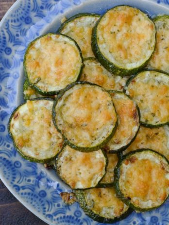 Overhead view of roasted zucchini with parmesan on plate with blue and white pattern