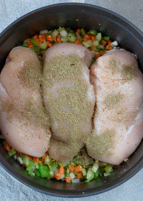 boneless, skinless chicken breasts and seasonings added to sauteed vegetables in a dutch oven