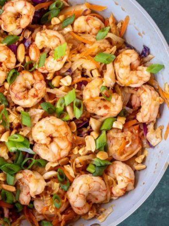 A pan of shrimp stir fry topped with scallions