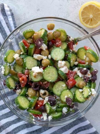 Overhead view of cucumber salad in glass bowl with spoon