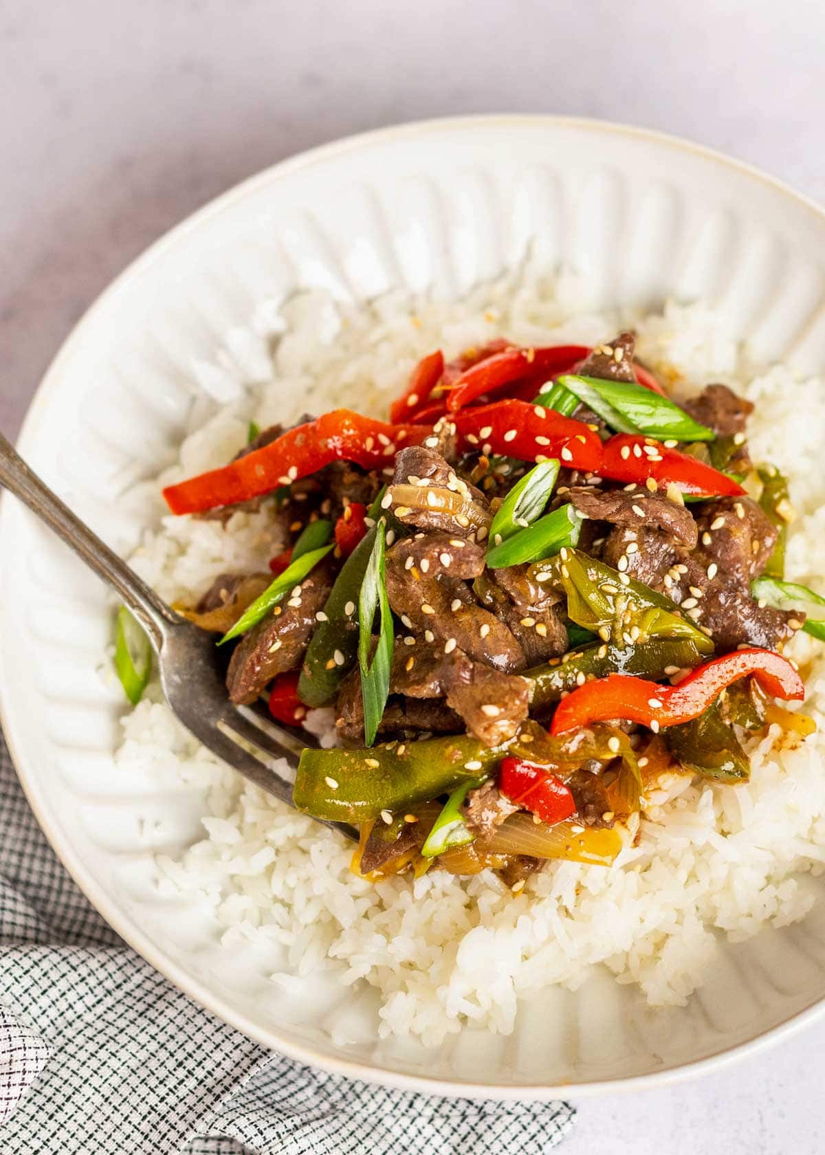 pepper steak on plate with rice and fork.