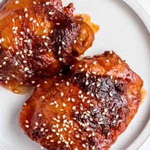 asian chicken thighs on plate with sesame seeds