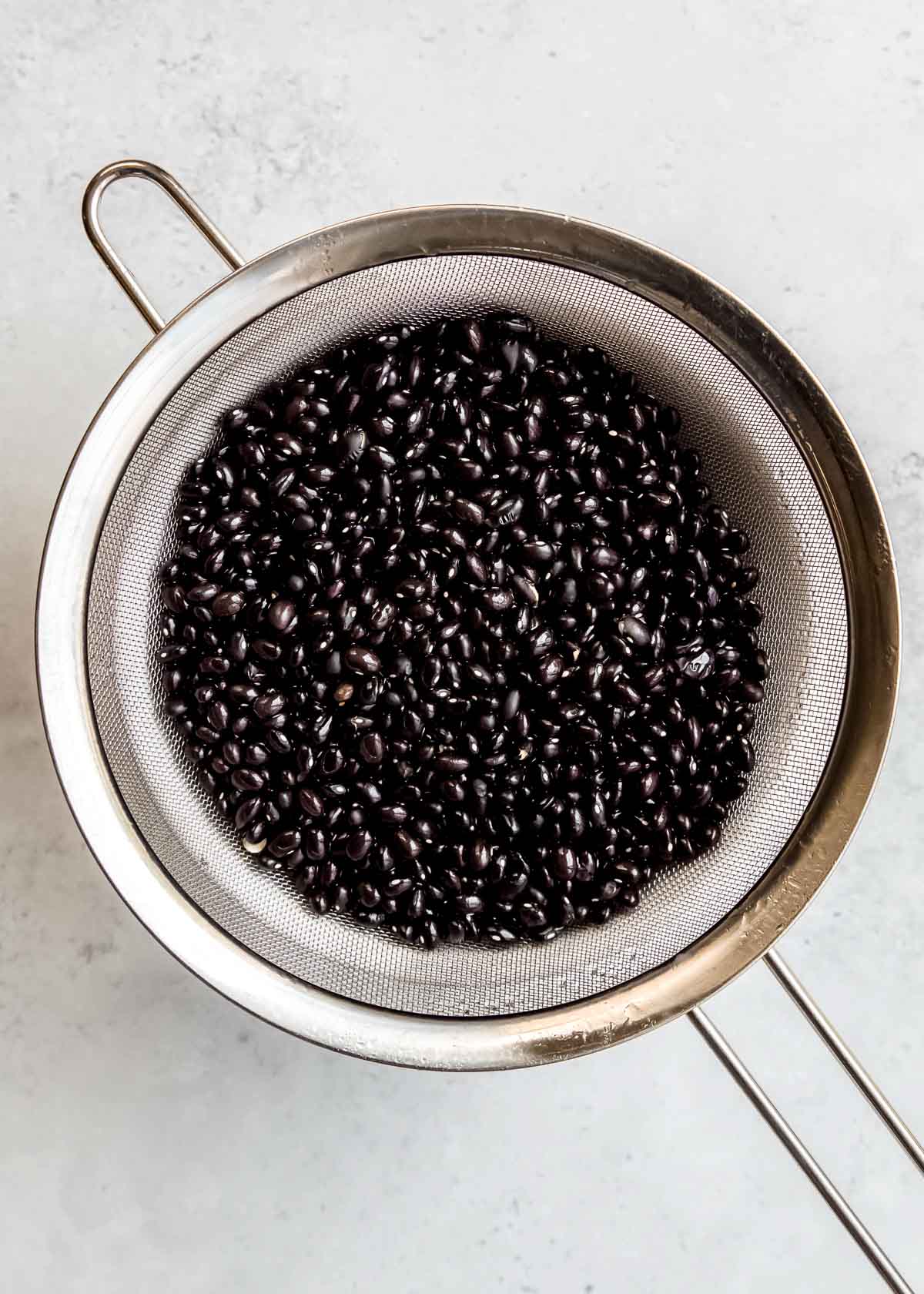 black beans being rinsed in strainer