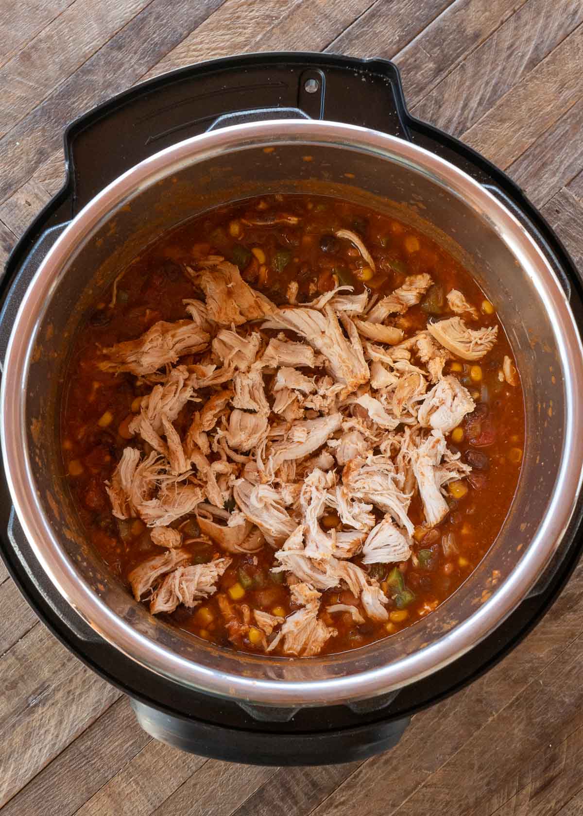 shredded chicken being placed in instant pot 