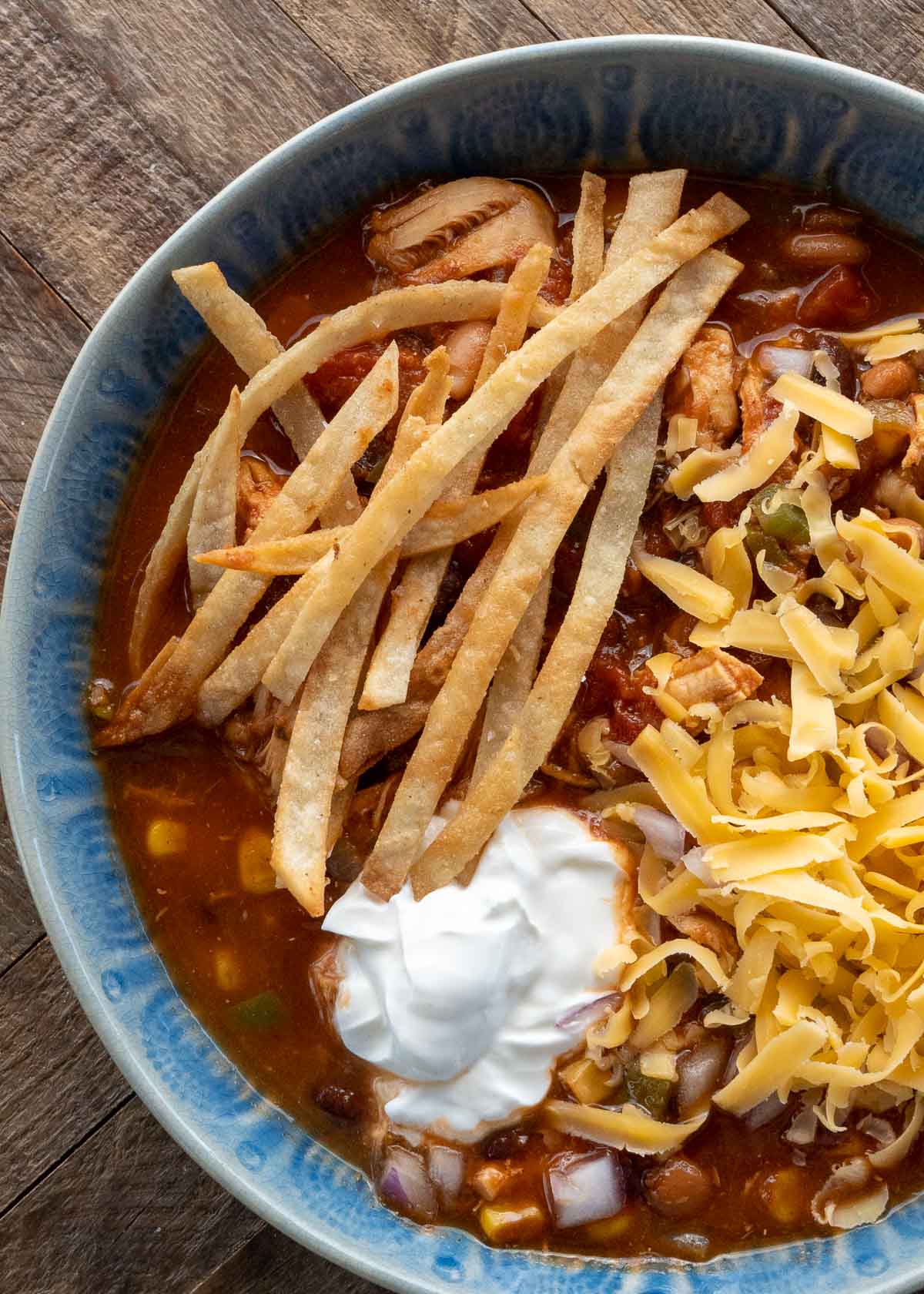 chicken tortilla soup in a blue bowl on a wooden table