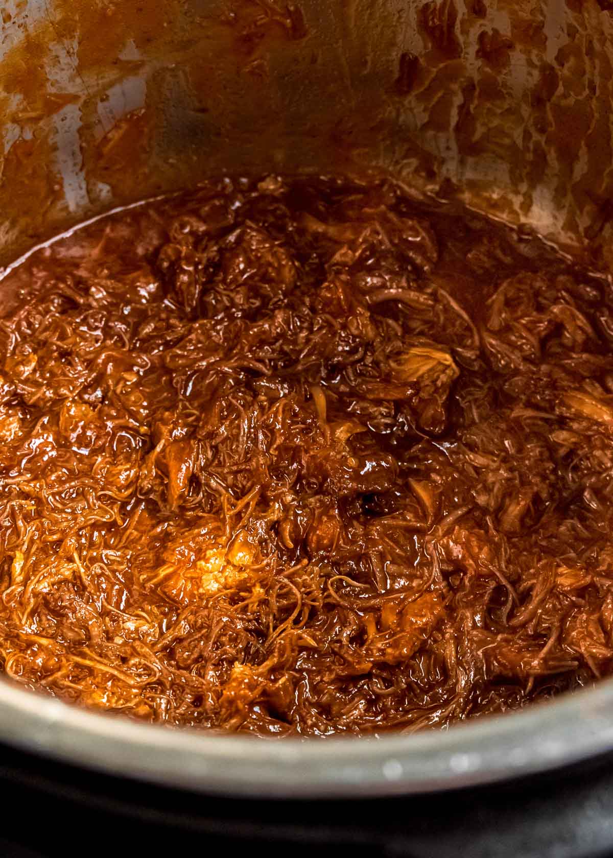 Juicy pulled pork shredded and covered in barbecue sauce in a large pot