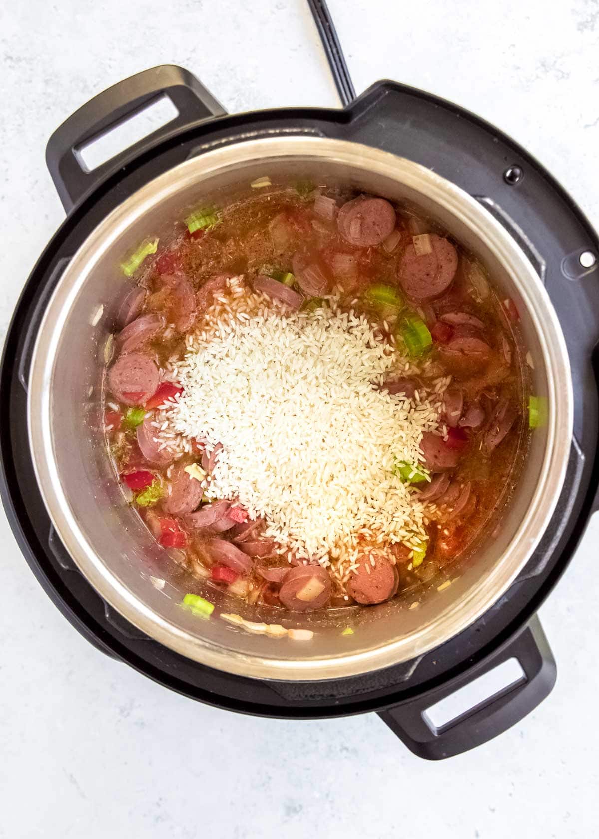 rice being added to instant pot red beans and rice