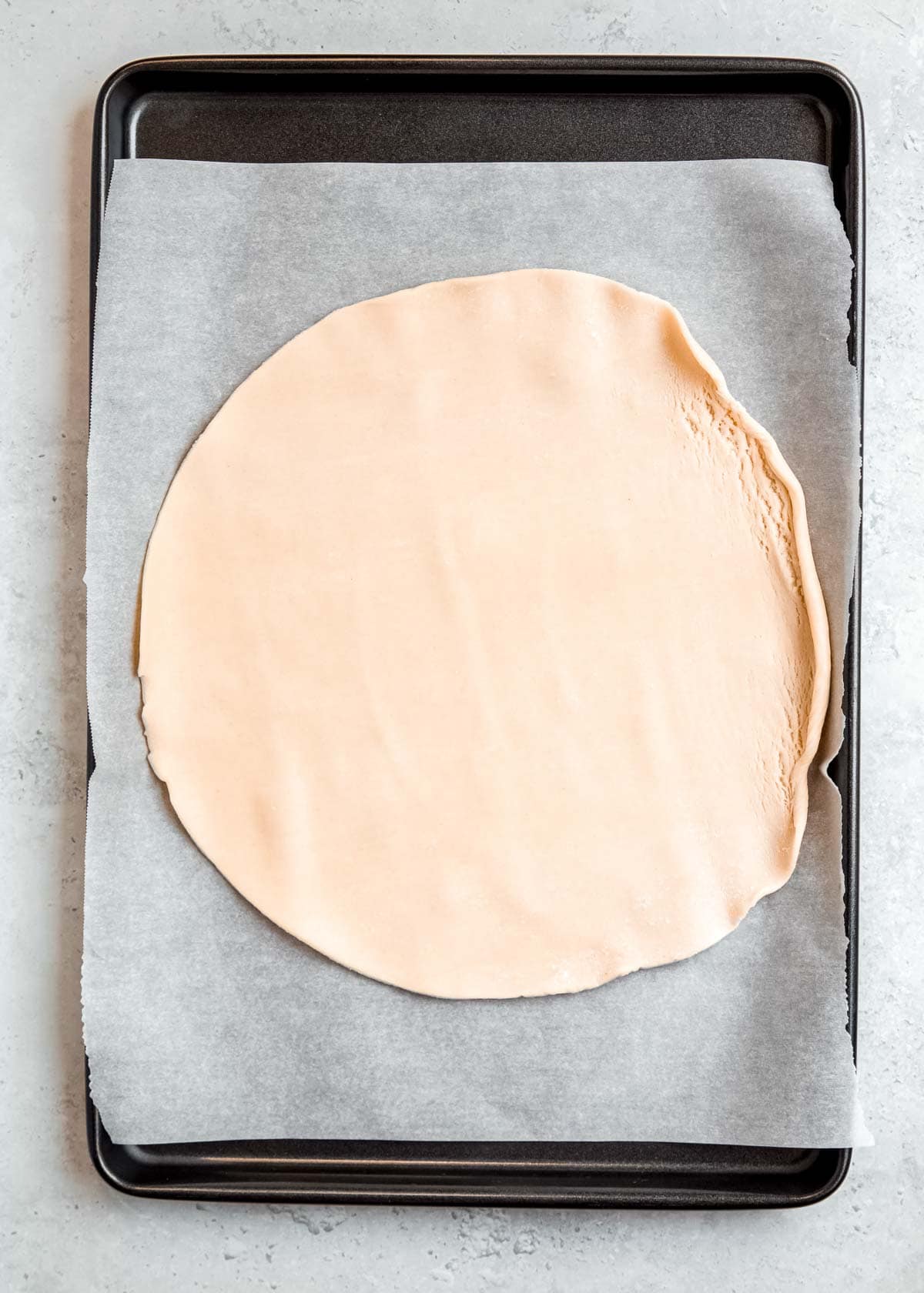 refrigerated pie crust unrolled on parchment paper