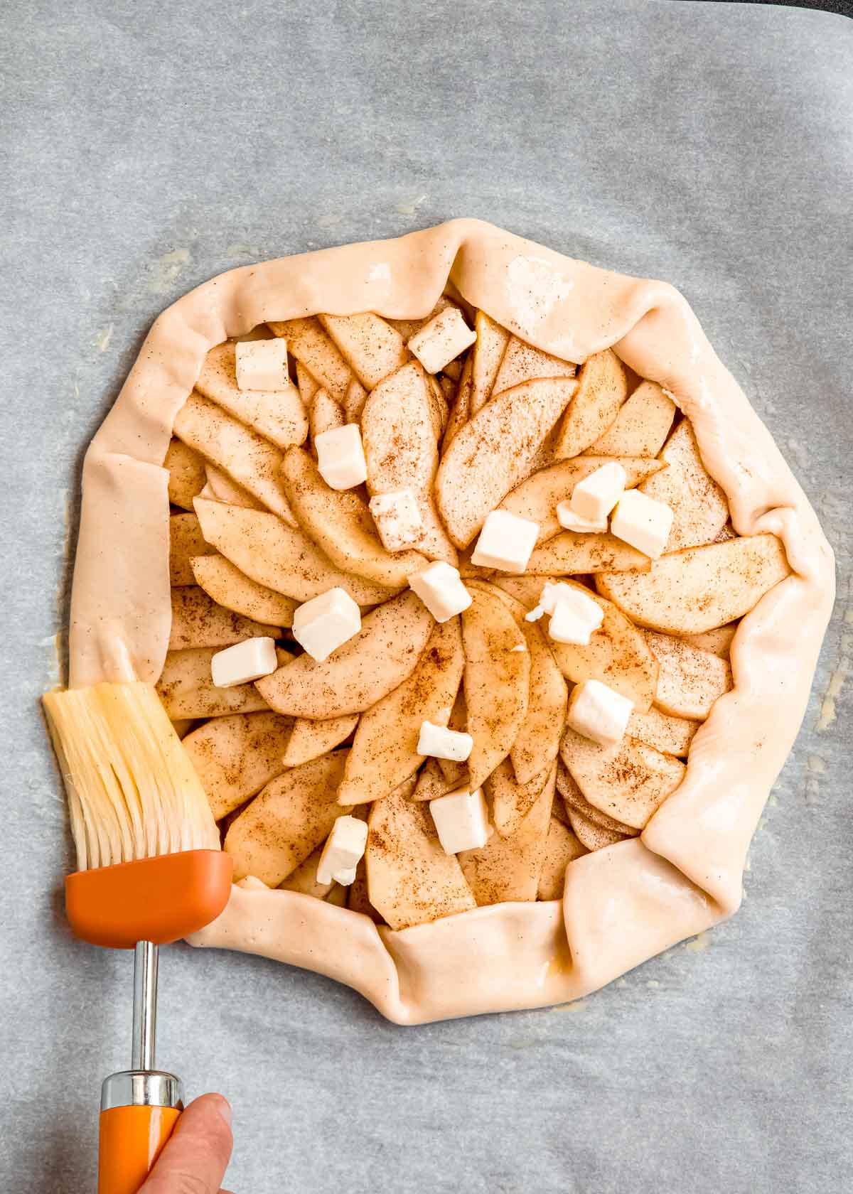 egg wash being brushed on apple galette crust