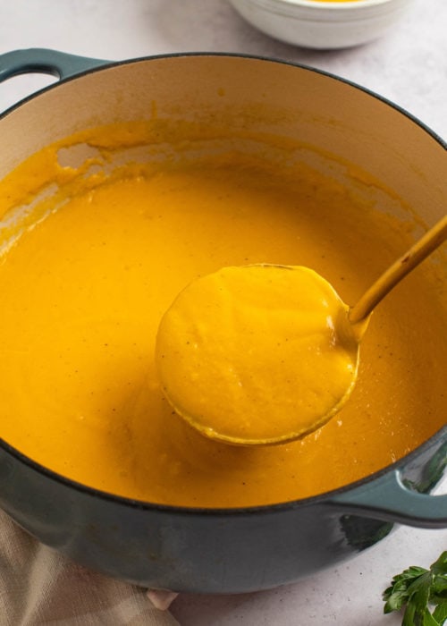 a large pot of easy butternut squash soup with a ladle.