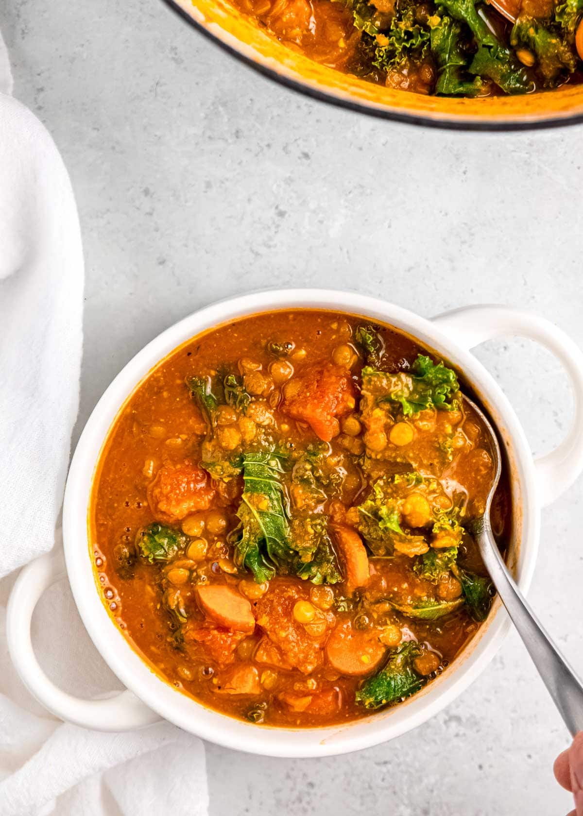 lentil soup being spooned from white bowl on white table