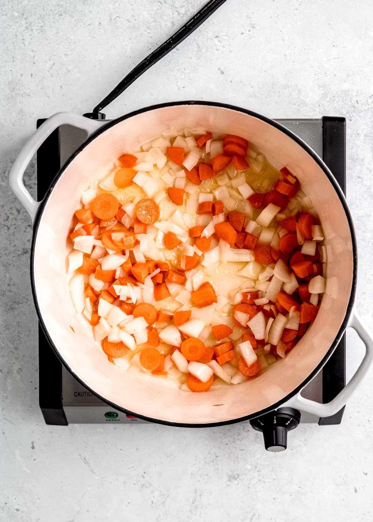 overhead view of onion and carrots being sauteed in a pot