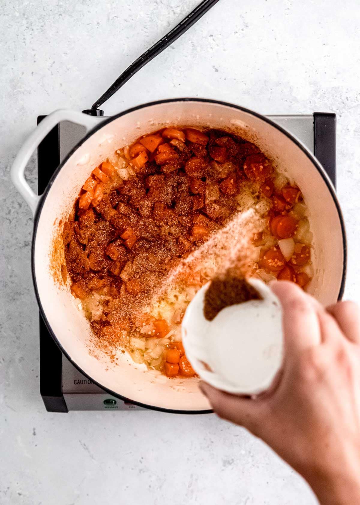 overhead shot of spices being added to lentil soup