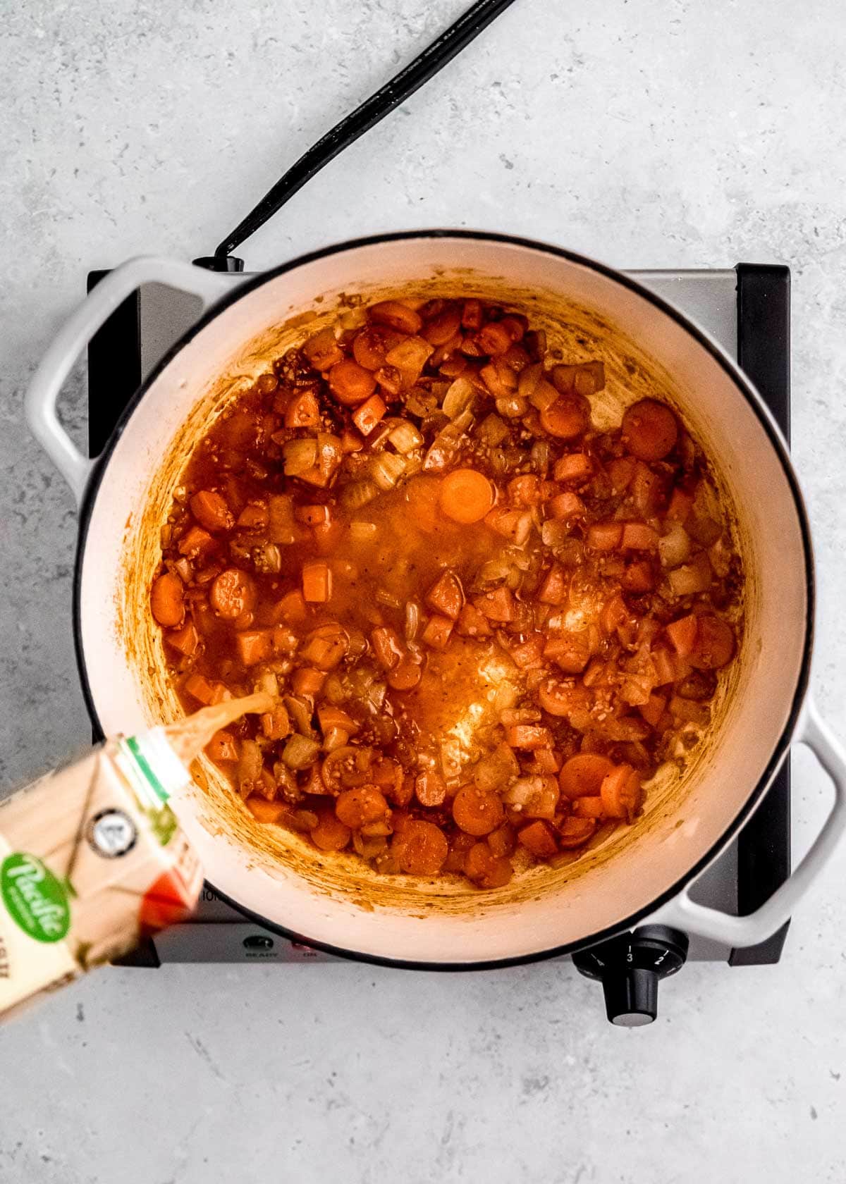 overhead shot of broth being added to lentil soup