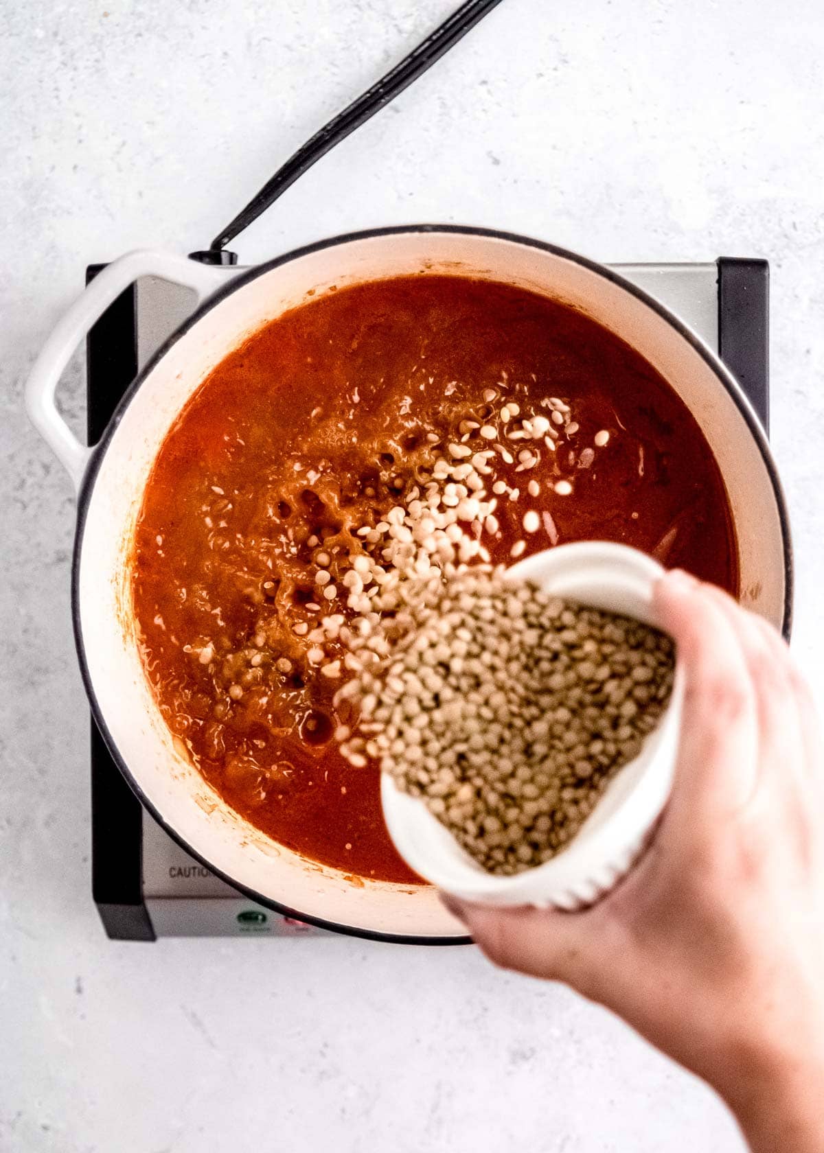 overhead shot of lentils being added to lentil soup