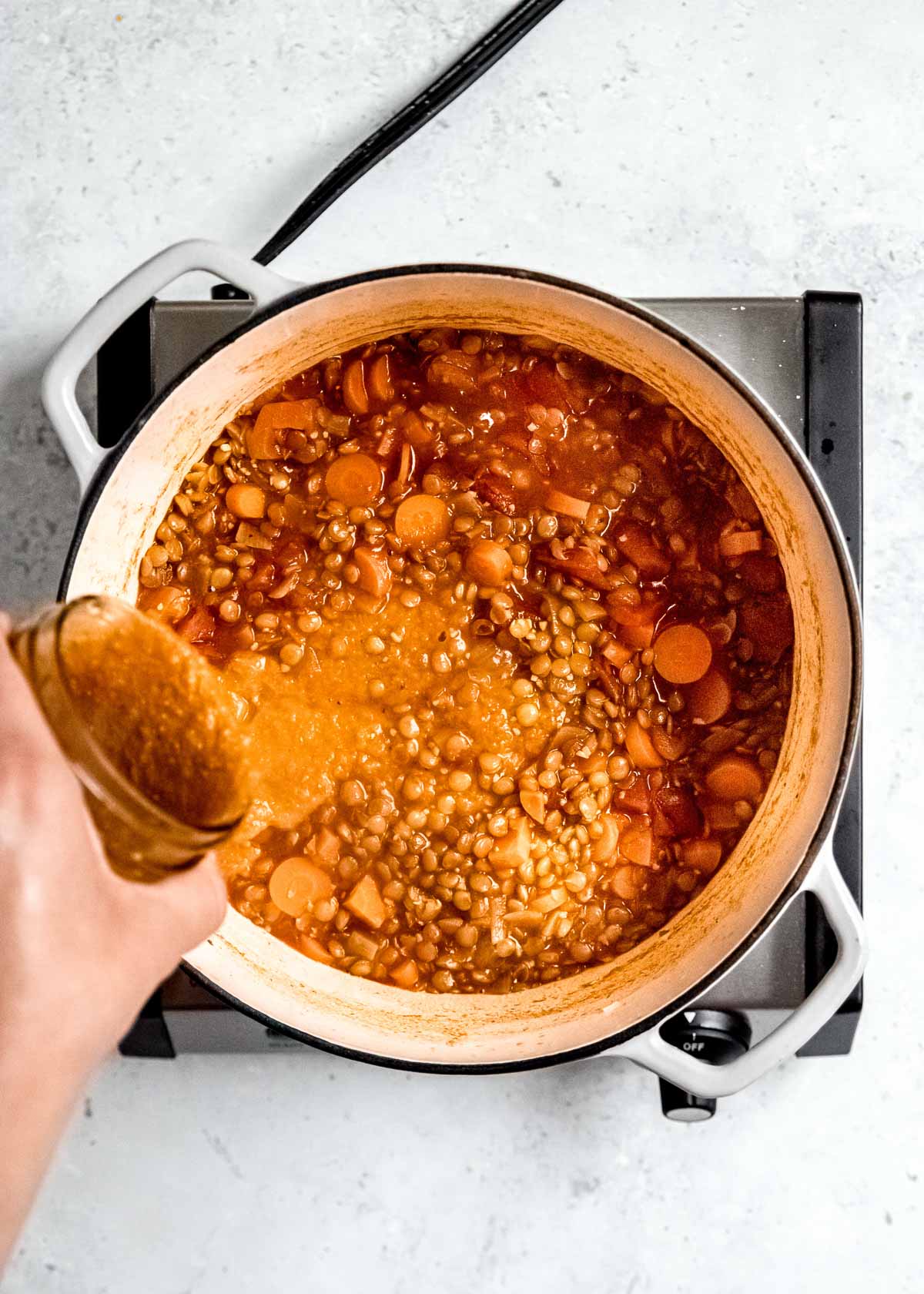 overhead shot of blended soup being added back to pot 