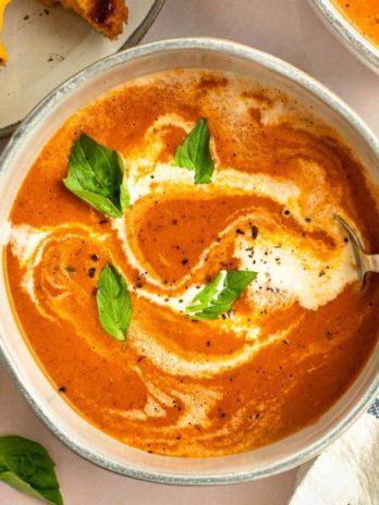 tomato soup in a bowl with a drizzle of heavy cream and basil