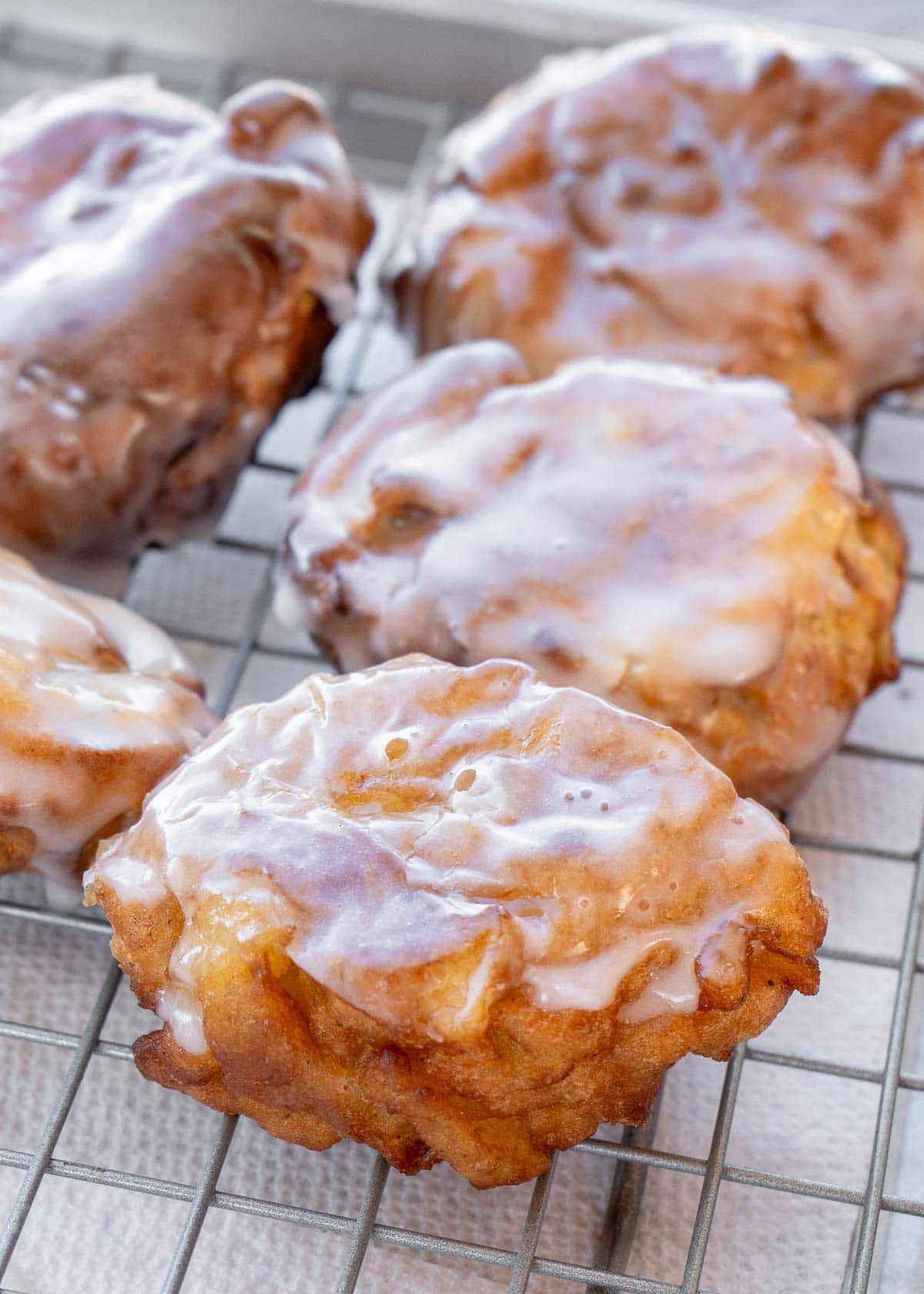 apple fritters on a cooling rack with glaze