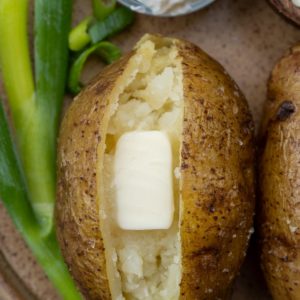 sliced baked potato with butter on brown plate