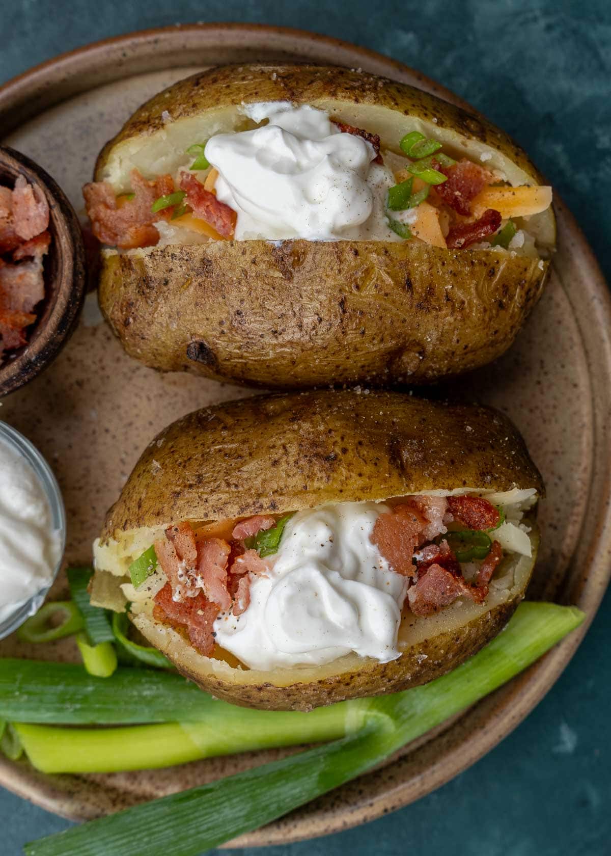 two loaded baked potatoes on brown plate