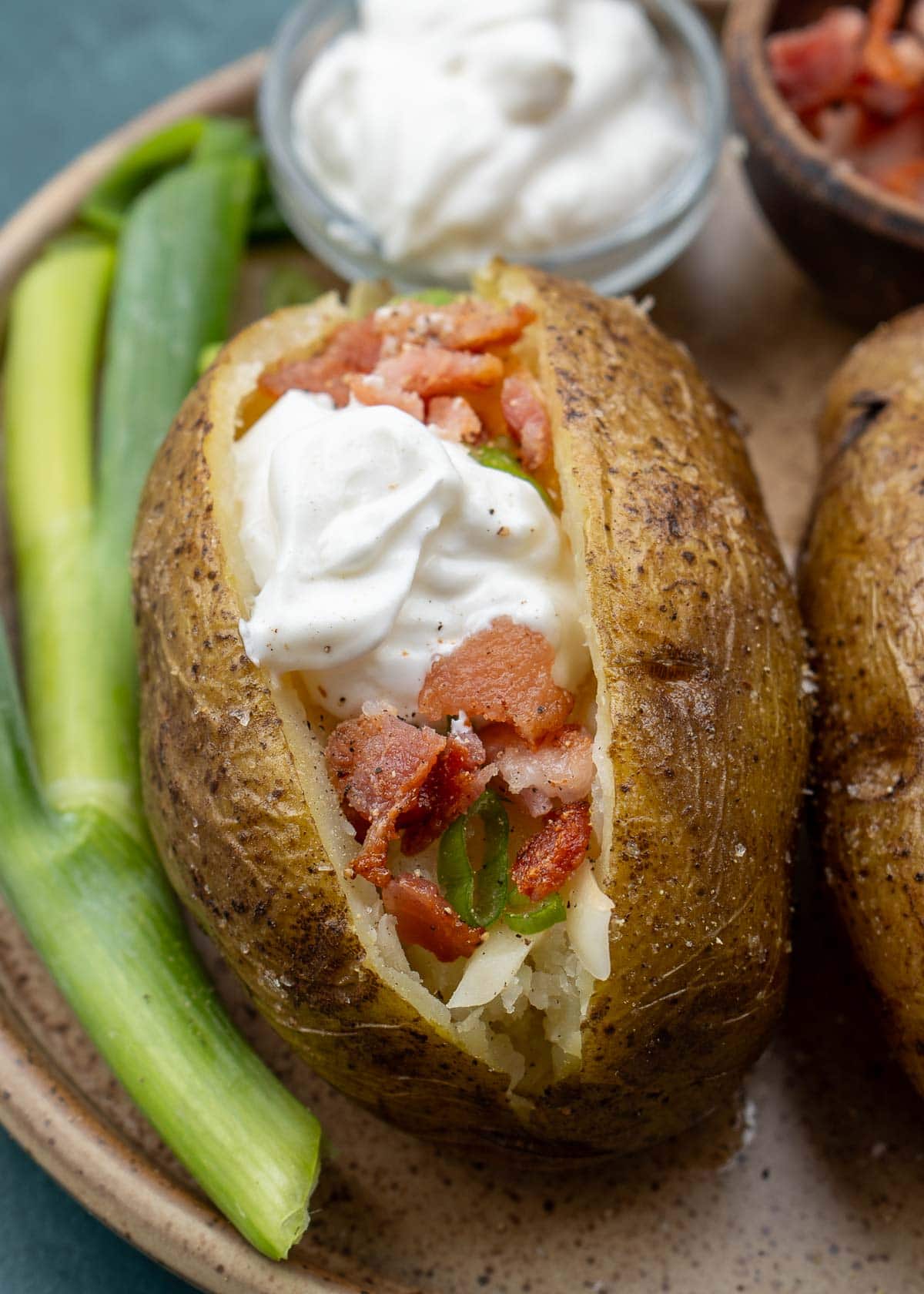 close up of loaded instant pot baked potato on brown plate