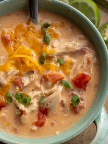 An overhead shot of cheesy rotel chicken soup in a blue bowl with a spoon