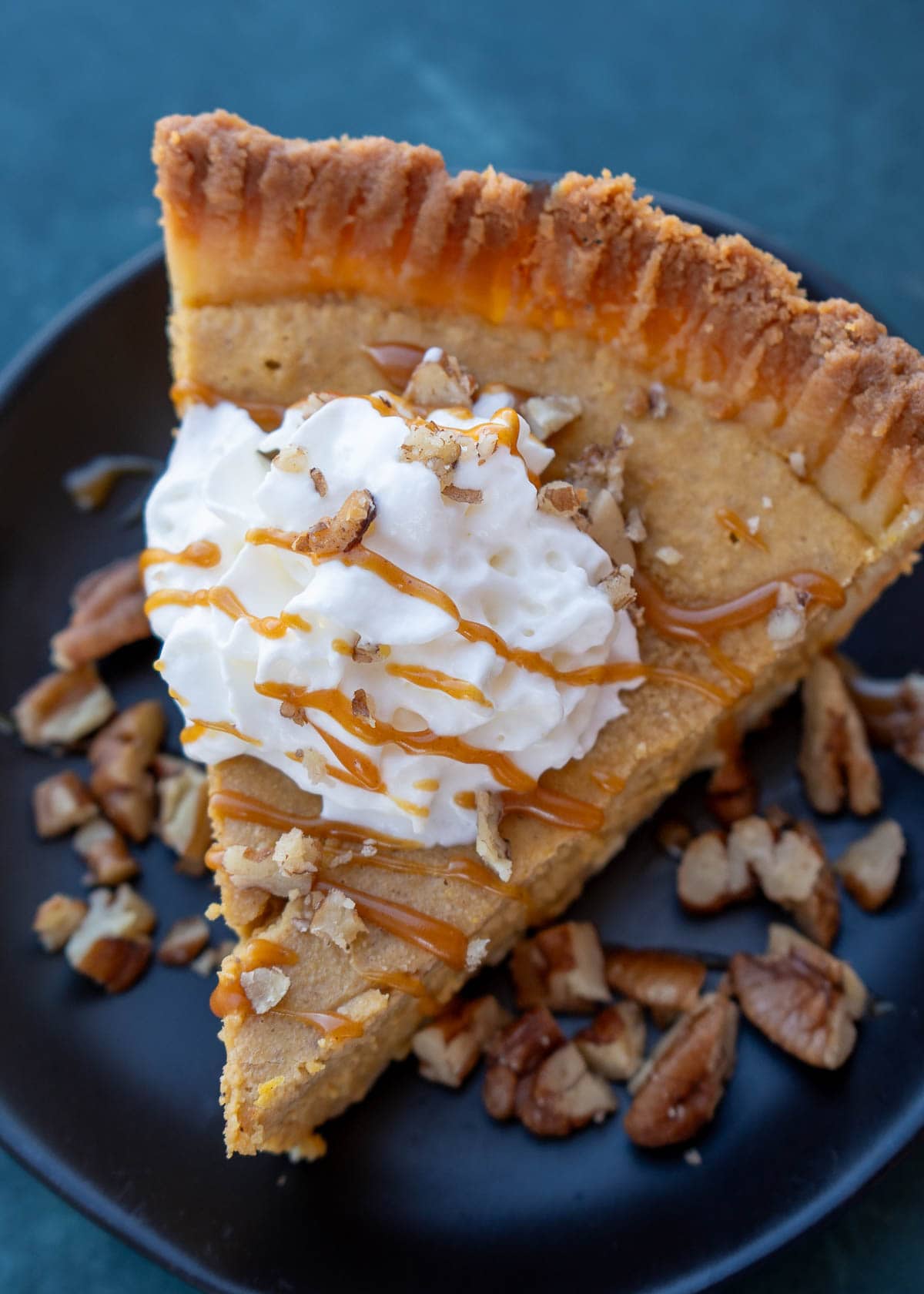 an overhead shot of gluten free pumpkin pie with whipped cream and caramel sauce