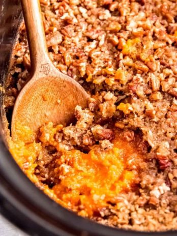 a slow cooker with sweet potato casserole with a brown sugar pecan topping