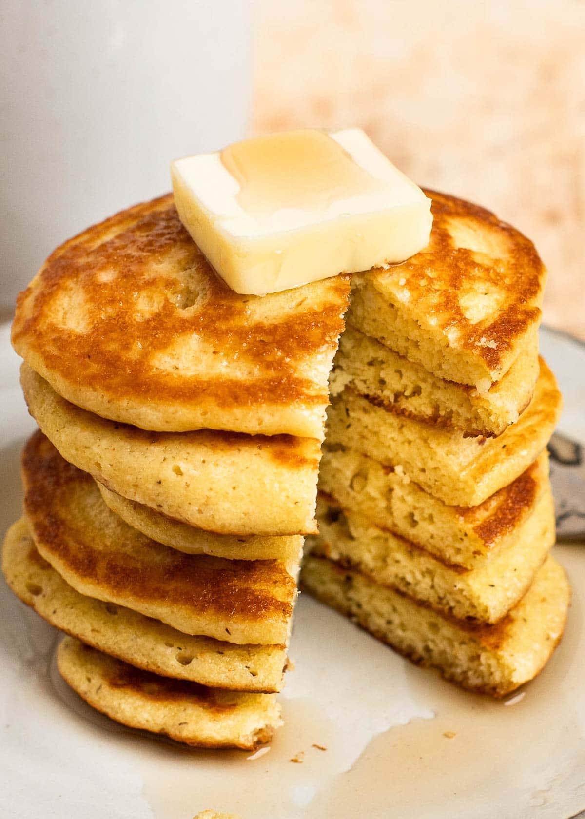 a stack of almond flour pancakes topped with a pat of butter and drizzled with maple syrup