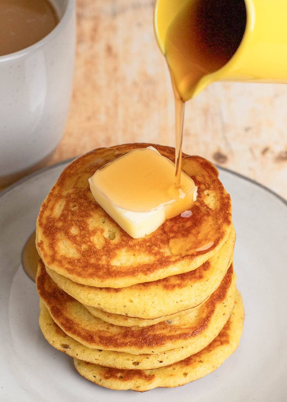 syrup being poured over almond flour pancakes