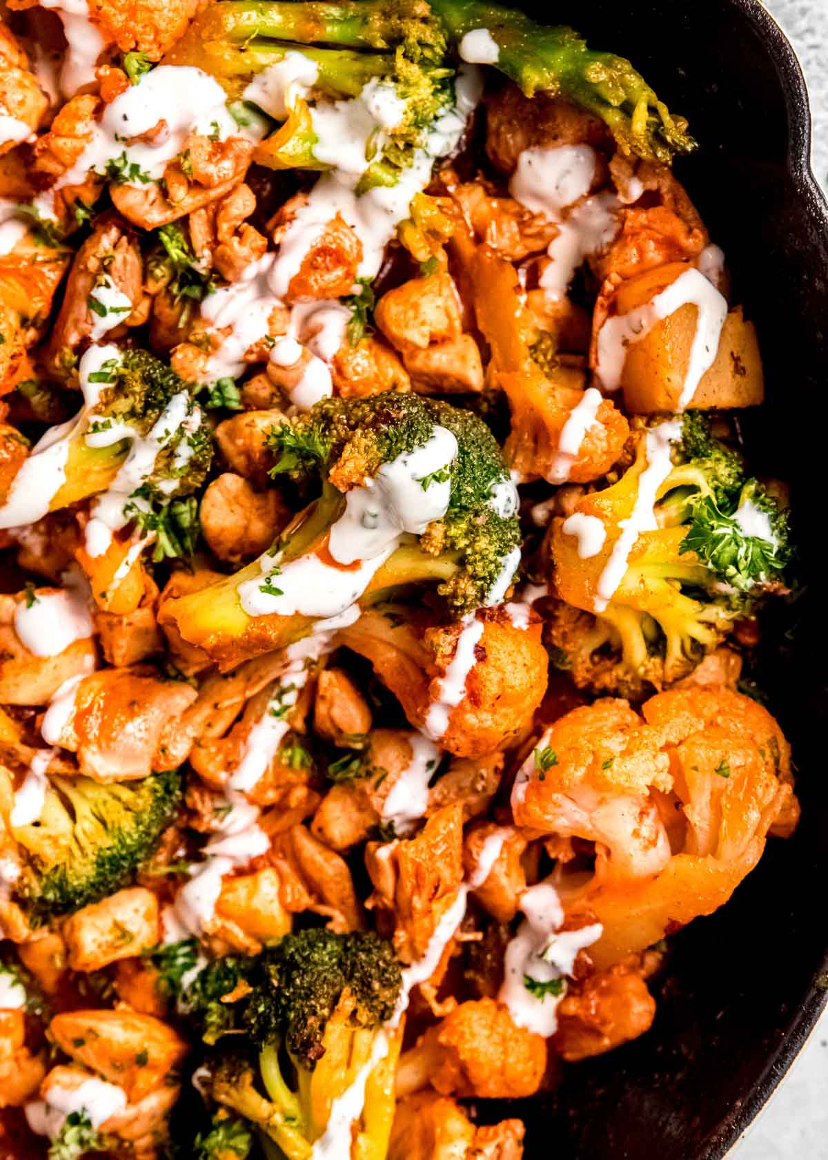 creamy dressing drizzled over a buffalo chicken skillet full of healthy veggies and juicy meat