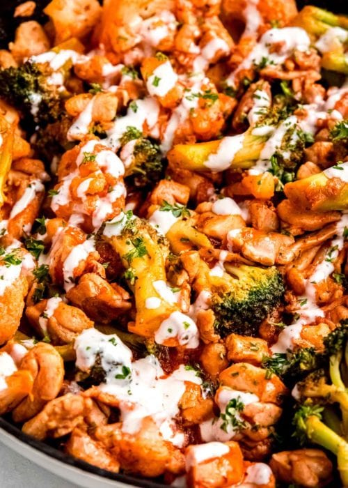 black skillet full of buffalo chicken, broccoli, and cauliflower for a delicious one pan meal