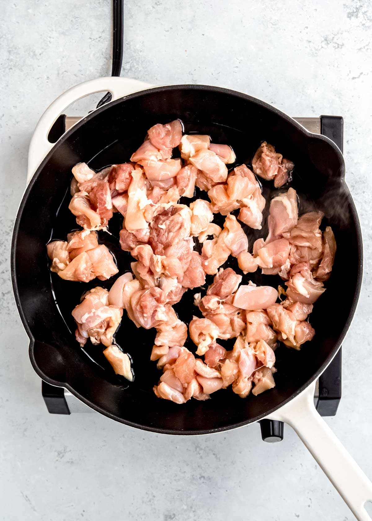 overhead image of raw chicken in a cast iron skillet