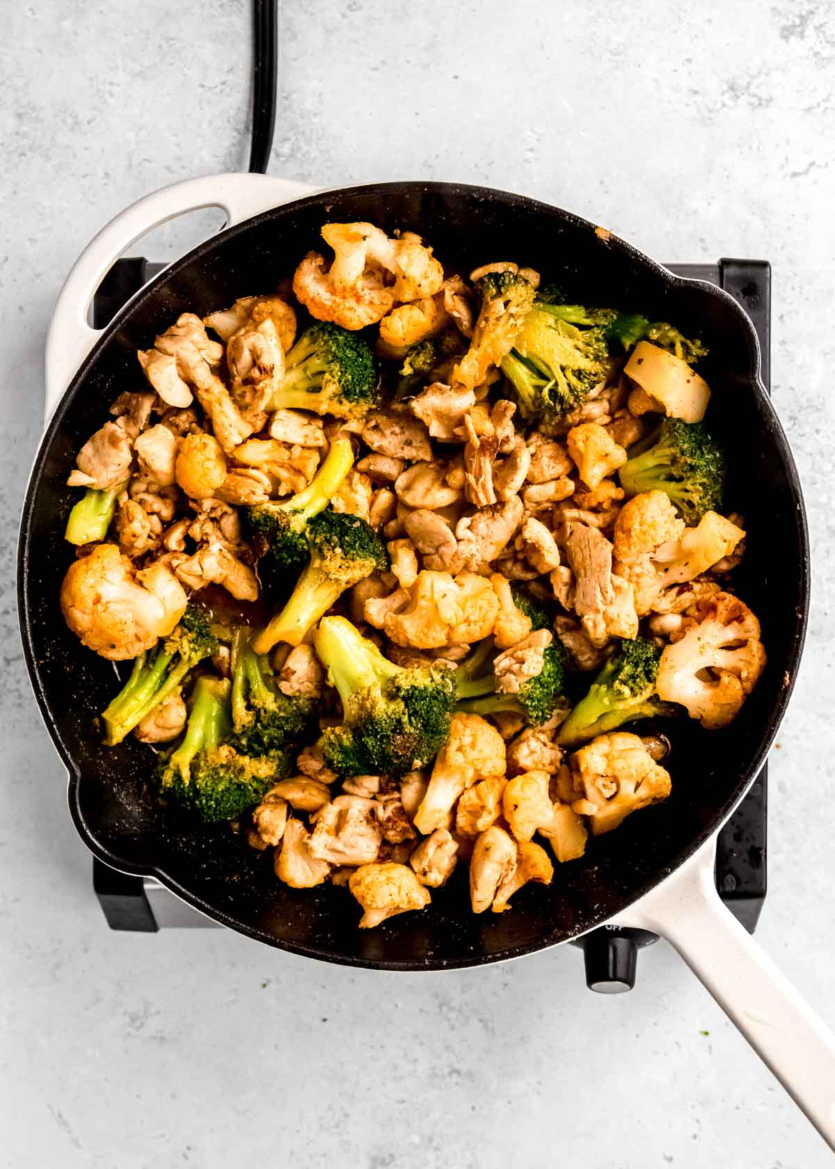 overhead image of seasoned chicken and veggies in cast iron skillet