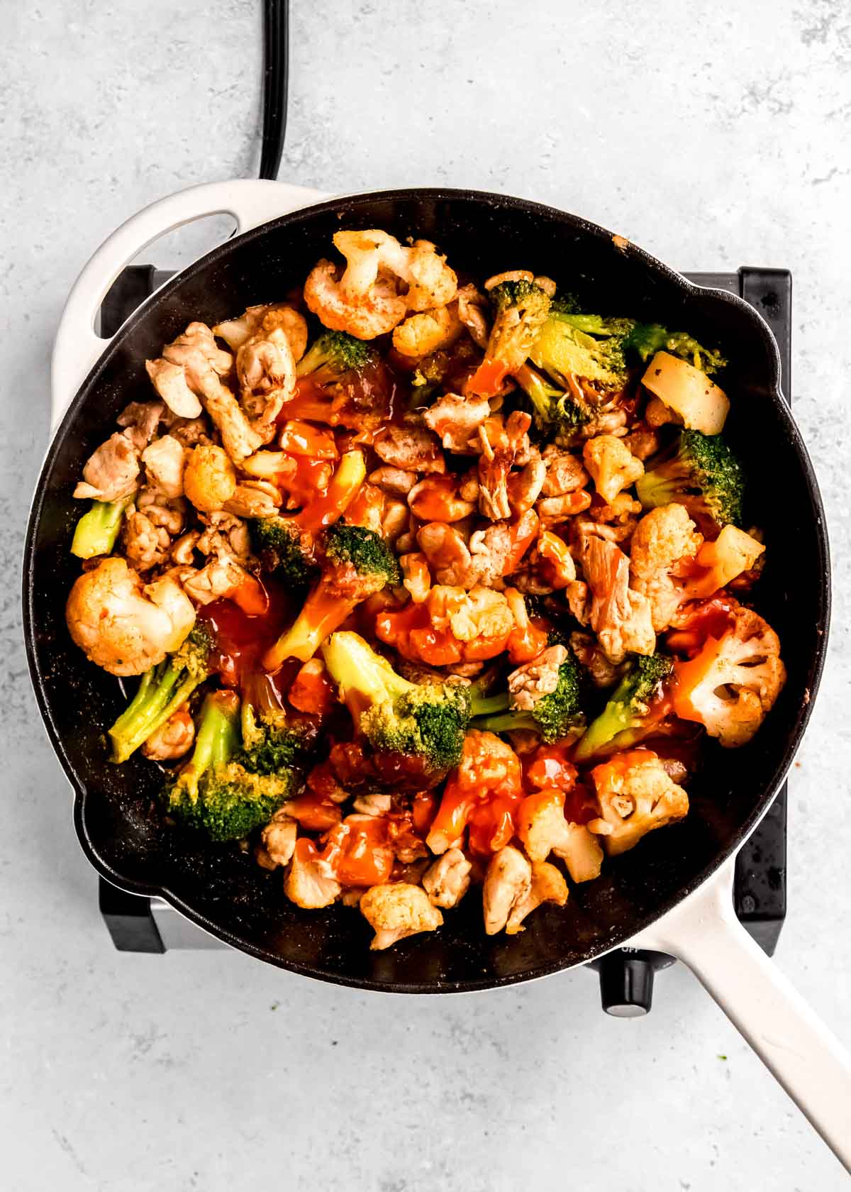 overhead image of buffalo sauce being added to cast iron skillet