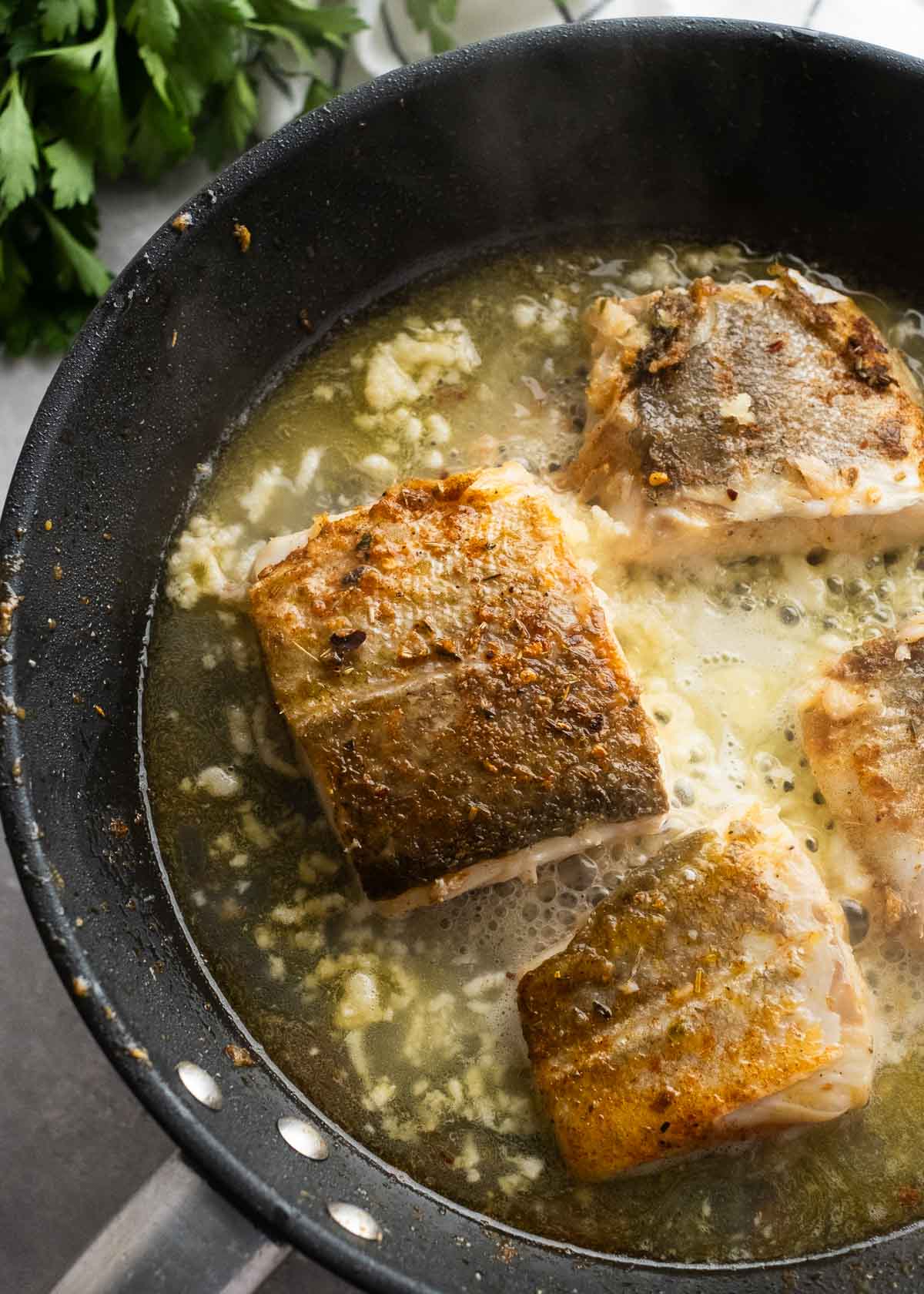 wet ingredients being added to skillet for garlic butter cod
