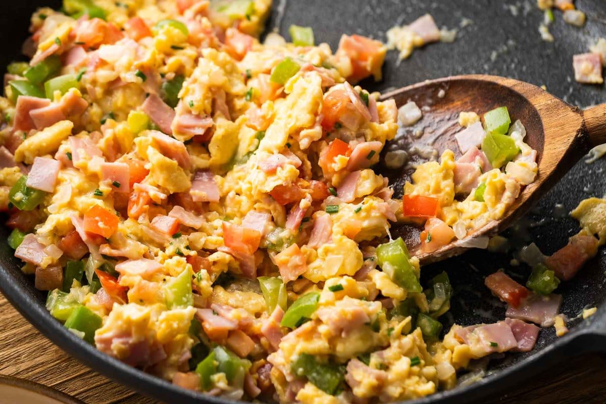 close up of loaded breakfast scramble being stirred in black skillet