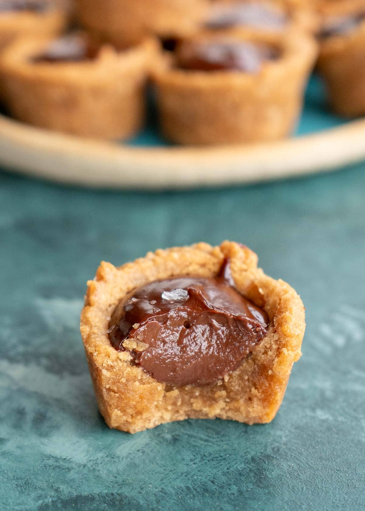 half of a chocolate peanut butter cookie cup in front of a plate full of the easy keto desserts