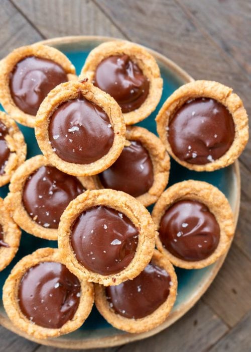 a plate piled high with peanut butter cookie cups filled with keto chocolate ganache