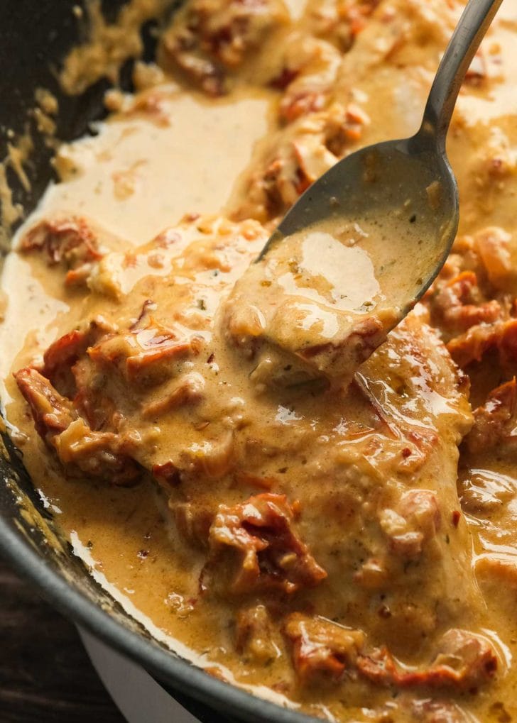 pouring sauce over chicken in pan