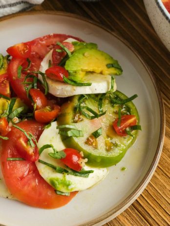 closeup of summer tomato salad with mozzarella, basil, and avocado