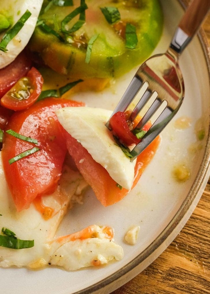 a fork with a bite of tomato and mozzarella salad