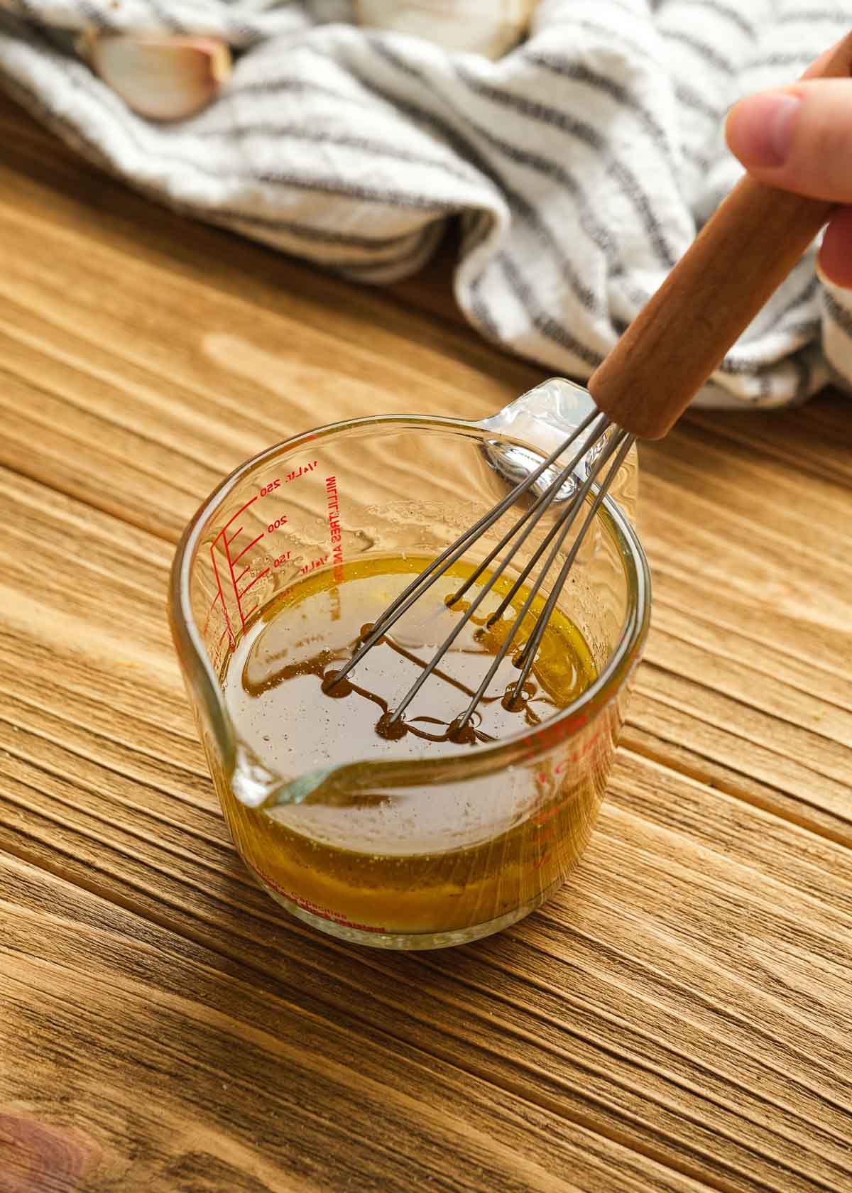 champagne vinaigrette ingredients in a measuring cup with a whisk