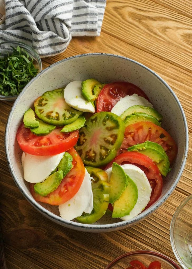 slices of tomatoes, mozzarella, and avocado in a large bowl