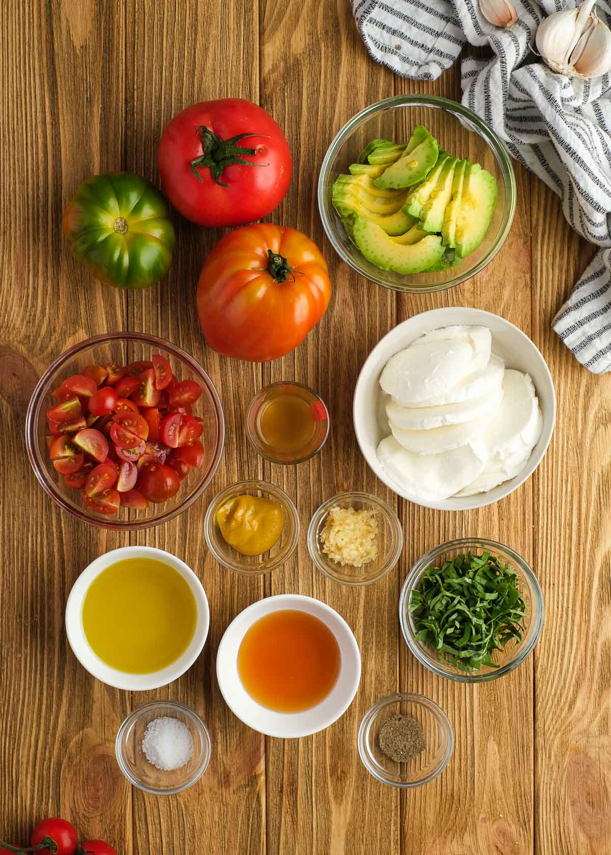 all ingredients for tomato and avocado salad on a wooden background