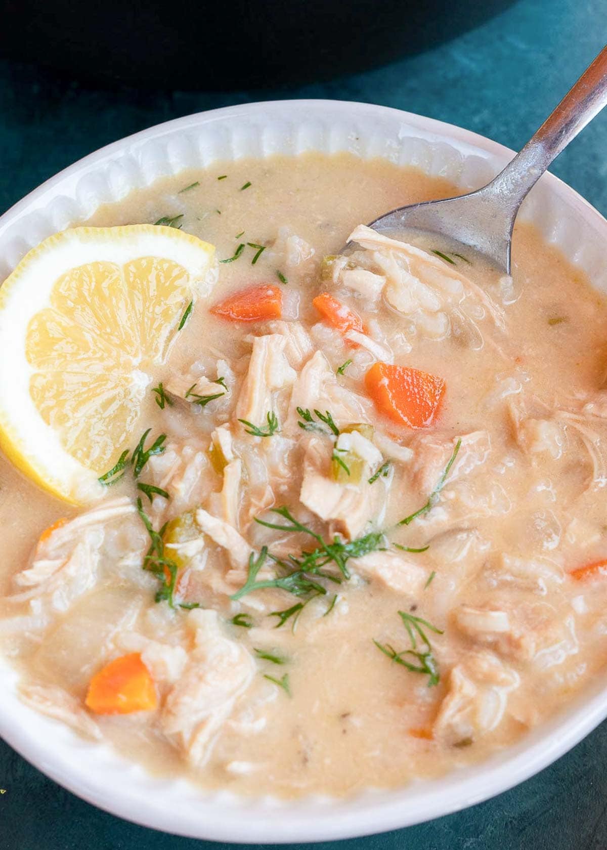 a spoon dipping into a rich and creamy bowl of avgolemono soup (or greek lemon chicken soup)