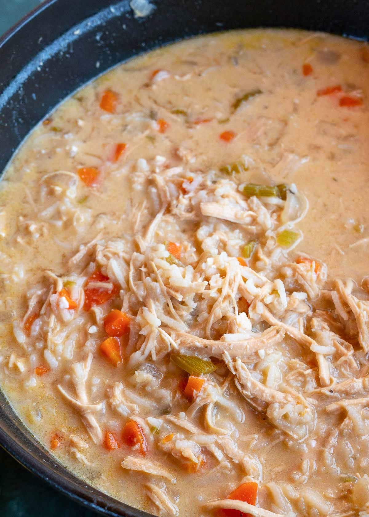 a large pot full of creamy avgolemono soup with chicken, rice, carrots, onion, and a rich lemon egg sauce