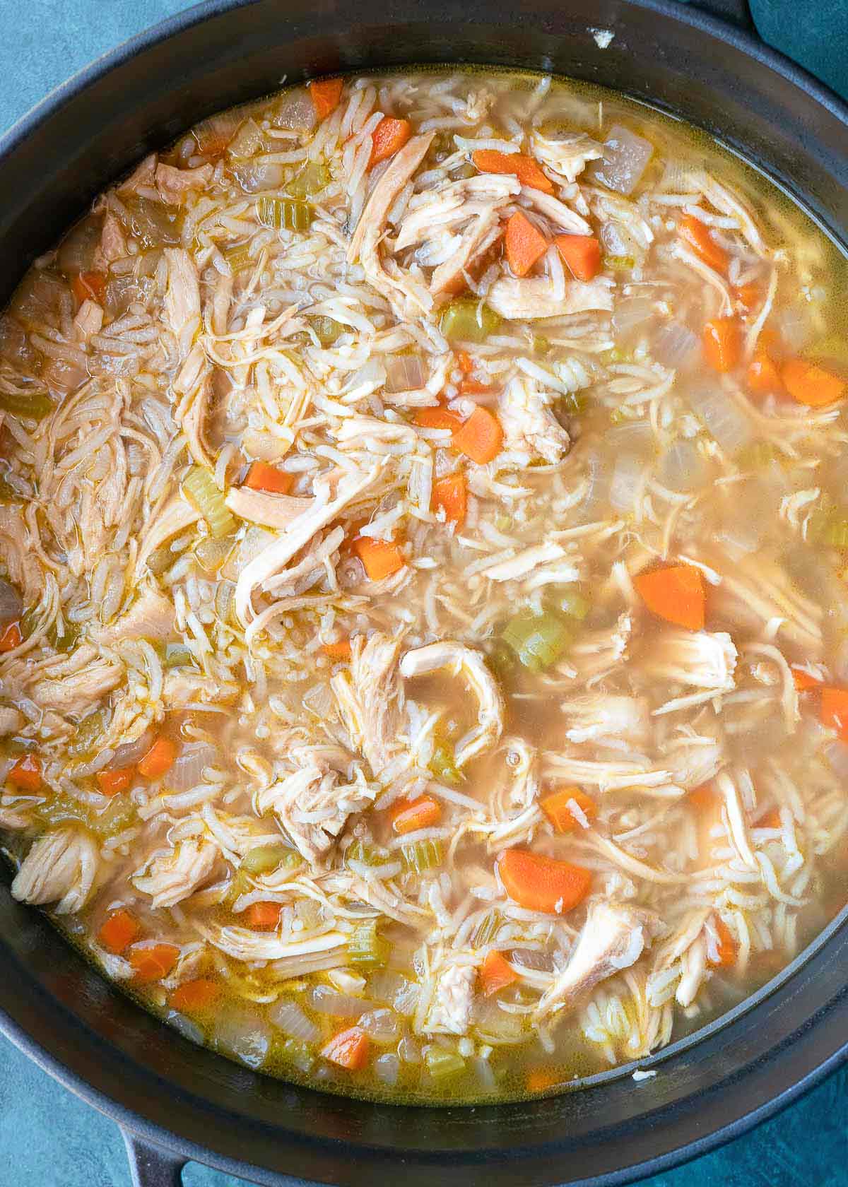 chicken broth being added to dutch oven with chicken and vegetables